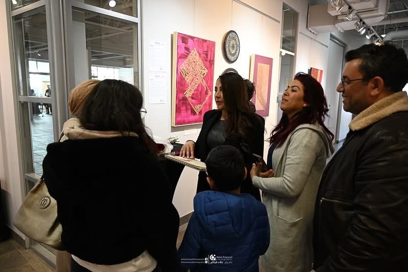 Hala Ali speaking with visitors at exhibition opening