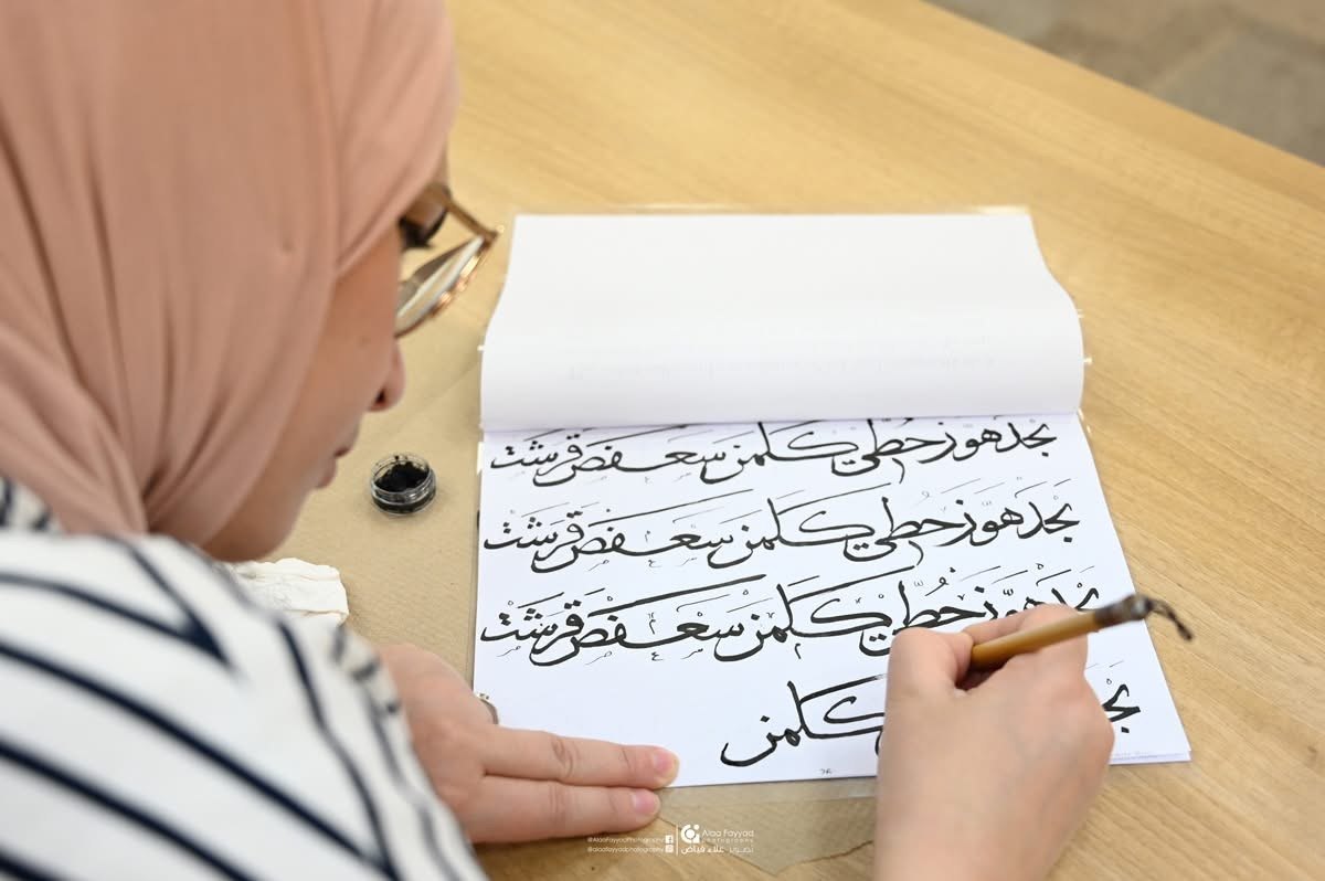 Workshop student practicing Arabic letterforms